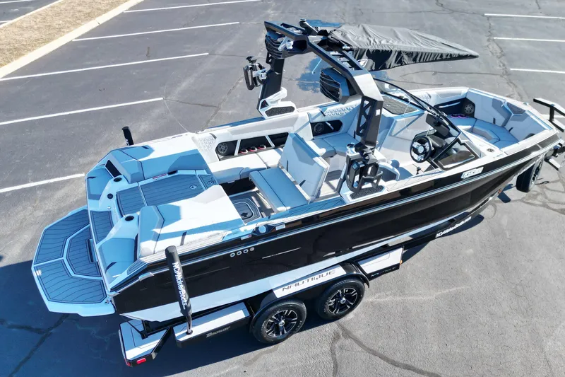 Slide: The Image of 2023 Nautique Super Air Nautique GS22 boat on trailer, black and white design, parked on asphalt. - 7