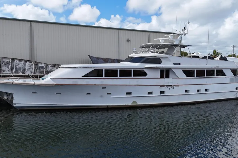 Slide: The Image of 1990 Denison Pilothouse Cockpit Motoryacht docked by a warehouse under a cloudy sky. - 3