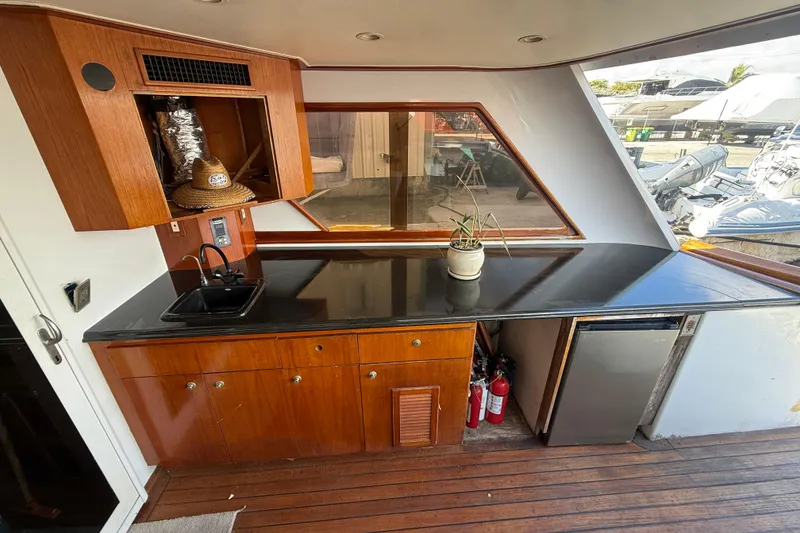Slide: The Image of 1990 Denison Pilothouse Cockpit Motoryacht interior with kitchenette, wooden cabinetry, and countertop. - 37