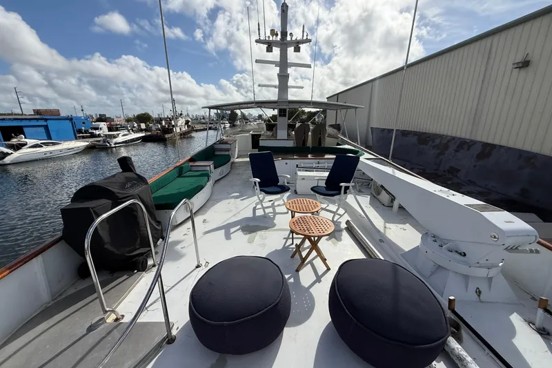 Slide: The Image of 1990 Denison Pilothouse Cockpit Motoryacht deck with seating and tables, docked at marina. - 54