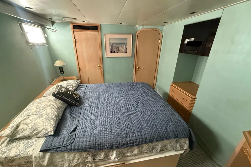 Slide: The Image of Cozy bedroom in 1990 Denison Pilothouse Cockpit Motoryacht with blue bedding and wooden accents. - 77
