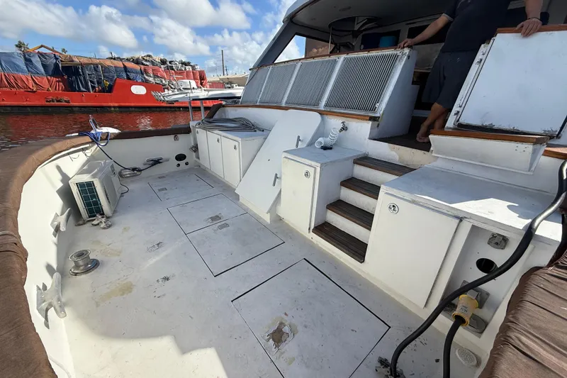 Slide: The Image of 1990 Denison Pilothouse Cockpit Motoryacht deck with storage compartments and steps, docked by a red ship. - 85