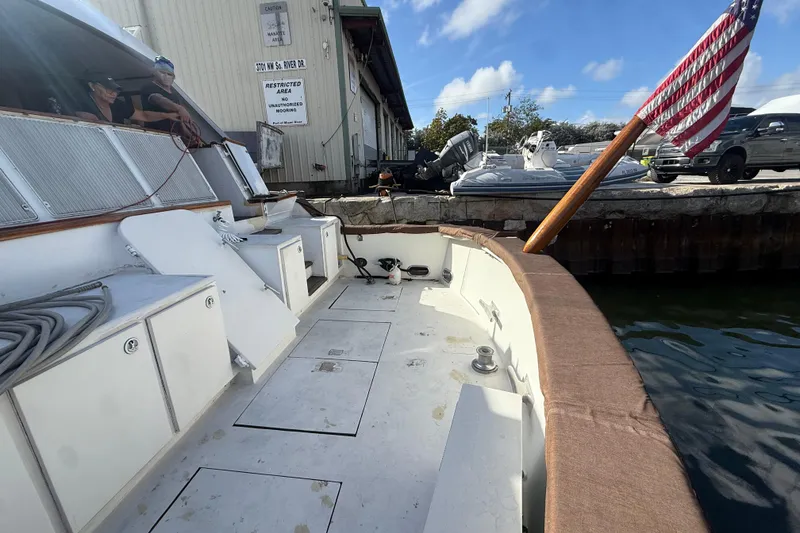 Slide: The Image of 1990 Denison Pilothouse Cockpit Motoryacht docked, featuring spacious deck and American flag. - 86