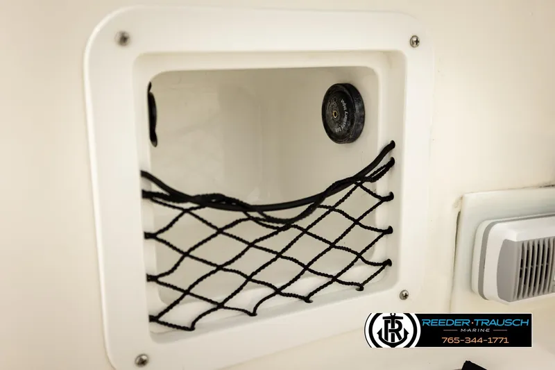 Slide: The Image of 2017 Bayliner Element F21 storage compartment with netting and speaker, Reeder-Trausch Marine logo. - 49