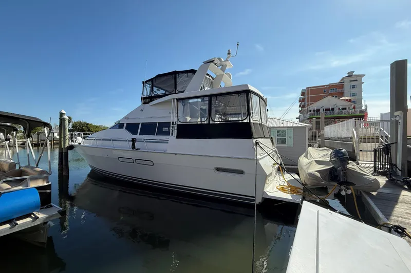 The Image of 1998 Mainship 47 Motor Yacht docked at marina under clear blue sky. - 0