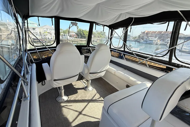Slide: The Image of 1998 Mainship 47 Motor Yacht interior with white seating and panoramic marina view. - 11