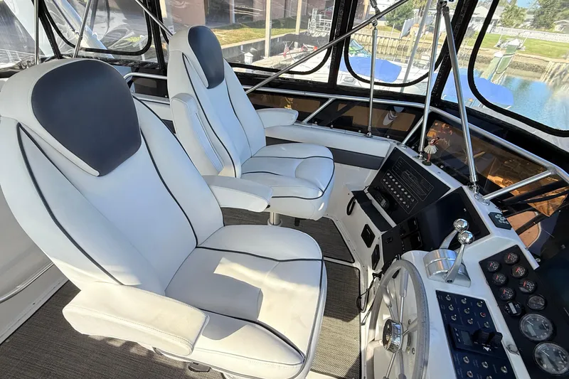 Slide: The Image of 1998 Mainship 47 Motor Yacht helm with dual white captain chairs and control panel. - 13