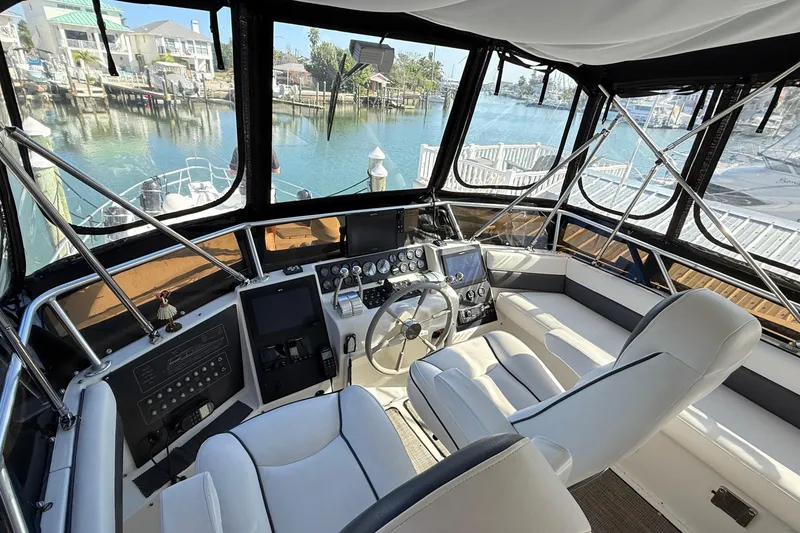 Slide: The Image of 1998 Mainship 47 Motor Yacht helm with modern controls, overlooking marina. - 16