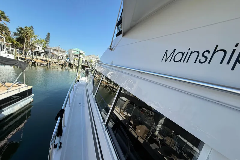 Slide: The Image of 1998 Mainship 47 Motor Yacht docked in a scenic marina setting. - 2