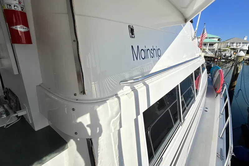 Slide: The Image of 1998 Mainship 47 Motor Yacht docked, showcasing sleek design and spacious deck. - 3