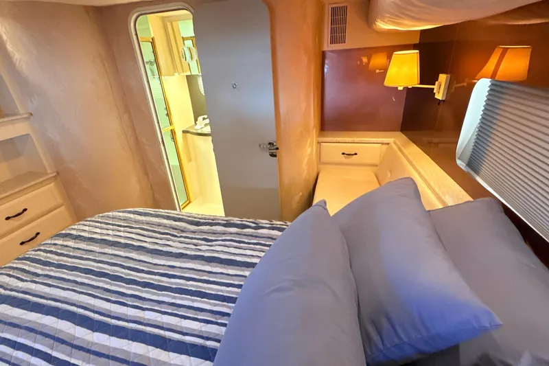 Slide: The Image of 1998 Mainship 47 Motor Yacht bedroom with striped bedding and warm lighting. - 44