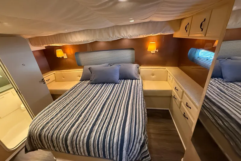 Slide: The Image of Cozy bedroom in 1998 Mainship 47 Motor Yacht with striped bedding and warm lighting. - 47