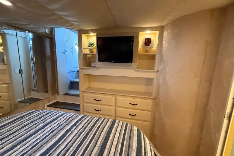 Slide: The Image of Cozy bedroom in 1998 Mainship 47 Motor Yacht with TV, drawers, and striped bedding. - 48