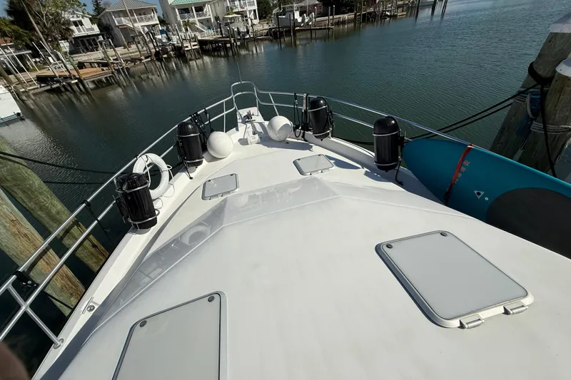 Slide: The Image of 1998 Mainship 47 Motor Yacht bow view at marina, featuring deck hatches and railings. - 5