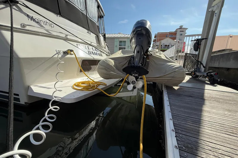 Slide: The Image of 1998 Mainship 47 Motor Yacht docked, with cables and covered outboard motor. - 6