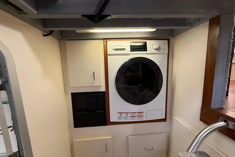 Slide: The Image of Laundry area inside 1998 Mainship 47 Motor Yacht with washer and storage cabinets. - 63