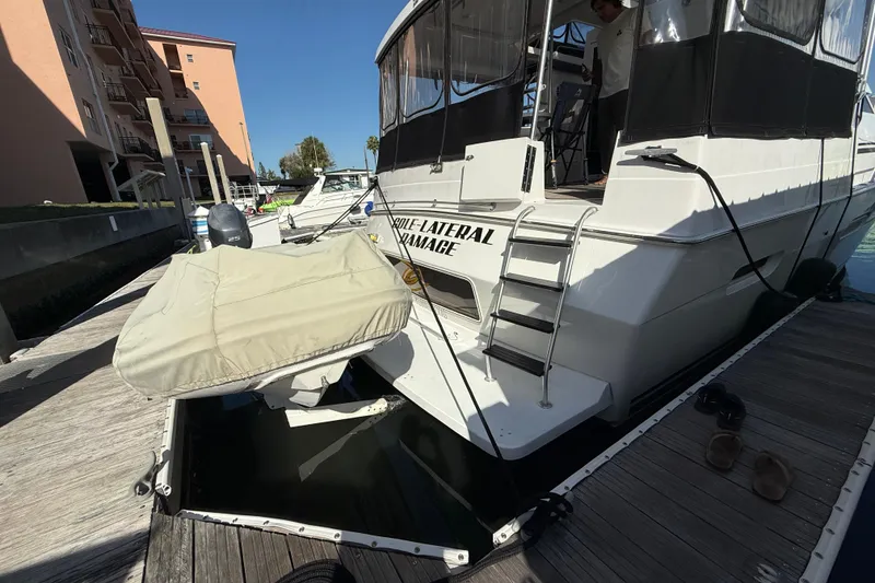 Slide: The Image of 1998 Mainship 47 Motor Yacht docked with covered dinghy and visible ladder. - 8
