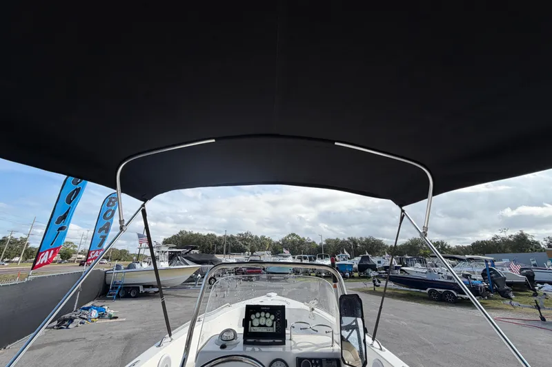 Slide: The Image of 2020 Key West 176 Sportsman CC boat with canopy, dashboard view, in a marina setting. - 20