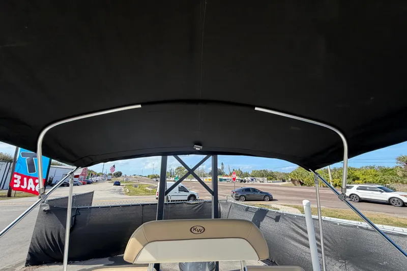 Slide: The Image of 2020 Key West 176 Sportsman CC boat with black canopy, parked near a road. - 45
