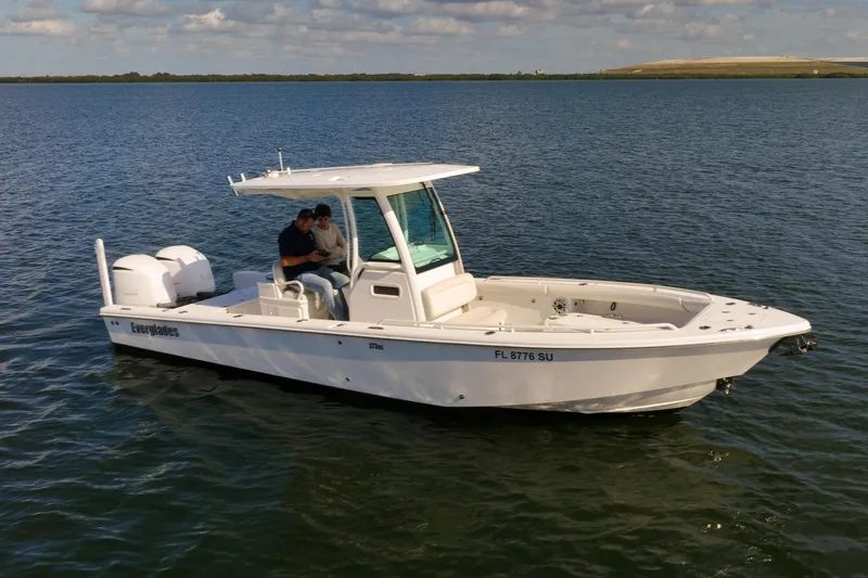 Slide: The Image of 2021 Everglades 273 Center Console boat on calm water, featuring dual engines. - 2
