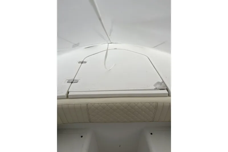 Slide: The Image of 2016 Southport 272 FE boat interior with white cushioned seating and storage compartment. - 5