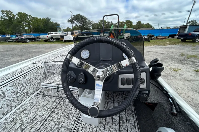 Slide: The Image of 2023 Crestliner 1600 Storm boat dashboard with steering wheel and controls, parked outdoors. - 10