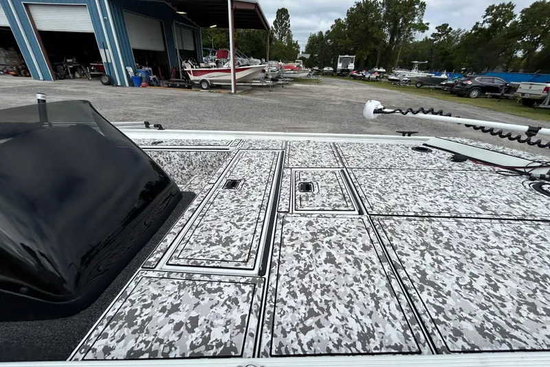 Slide: The Image of 2023 Crestliner 1600 Storm boat with camo deck, parked near a blue warehouse. - 6