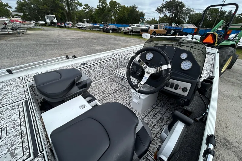 Slide: The Image of 2023 Crestliner 1600 Storm boat interior with steering wheel and seats in a parking lot. - 8