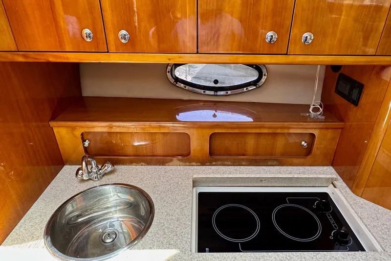 Slide: The Image of 2009 Regal 4080 yacht kitchen with sink, stove, and wooden cabinets. - 19