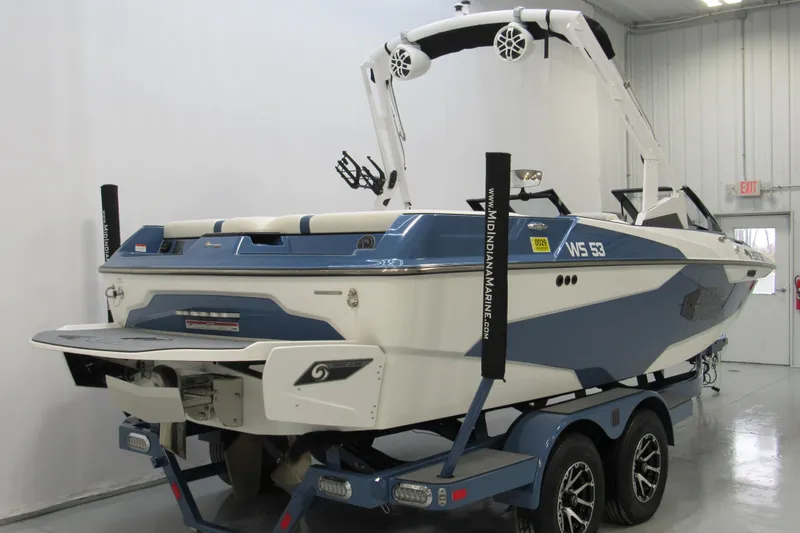 Slide: The Image of 2021 Axis A20 boat in showroom, blue and white design, on trailer. - 2