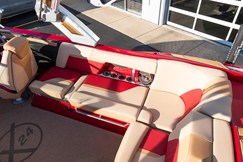 Slide: The Image of 2022 MasterCraft X24 boat interior with red and beige seating, cup holders, and speaker. - 12