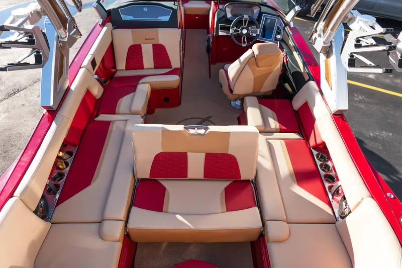 Slide: The Image of 2022 MasterCraft X24 boat interior with red and beige seating, modern dashboard, and cup holders. - 16