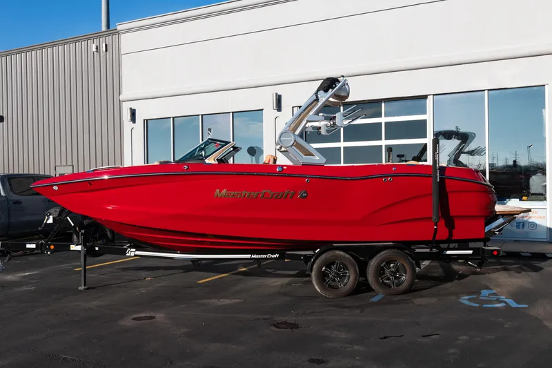 Slide: The Image of 2022 MasterCraft X24 boat in vibrant red on a trailer outside a showroom. - 2