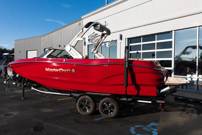 Slide: The Image of 2022 MasterCraft X24 boat in vibrant red on a trailer, parked outside a building. - 3
