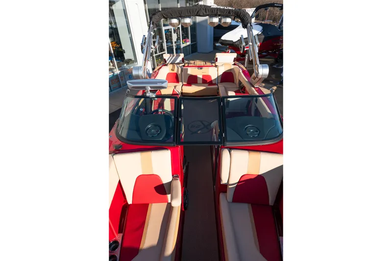 Slide: The Image of 2022 MasterCraft X24 boat interior with red and beige seating, open windshield, and tower speakers. - 37