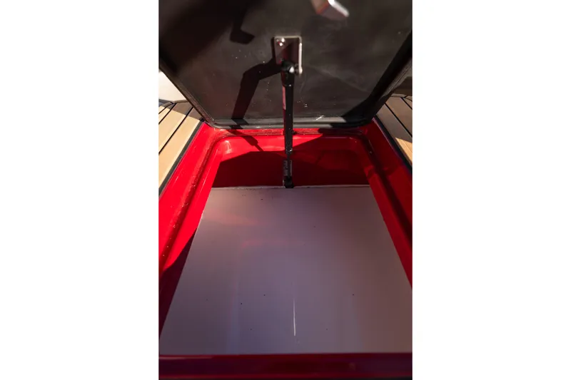 Slide: The Image of Open storage compartment in 2022 MasterCraft X24 boat, featuring red interior. - 41
