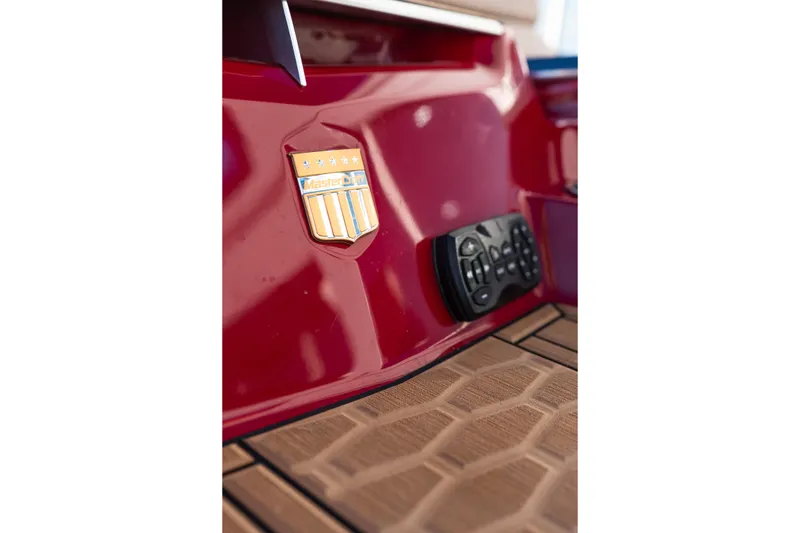 Slide: The Image of Red 2022 MasterCraft X24 boat detail with emblem and control panel on deck. - 49