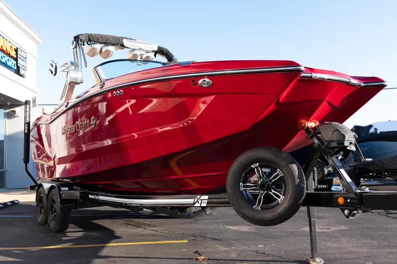 Slide: The Image of Red 2022 MasterCraft X24 boat on trailer, parked outdoors. - 51