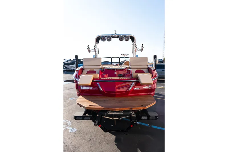 Slide: The Image of 2022 MasterCraft X24 boat, rear view, red exterior, beige seating, parked on pavement. - 7