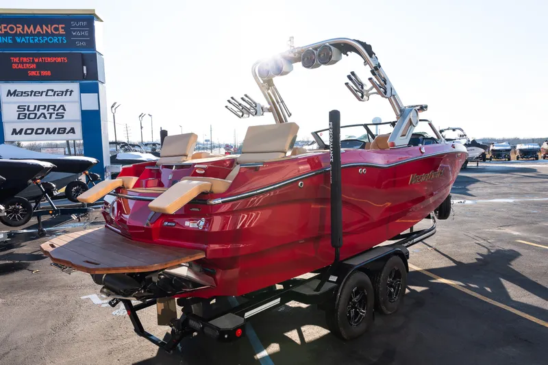 Slide: The Image of Red 2022 MasterCraft X24 boat on trailer at dealership, sunny day. - 8