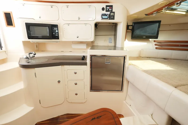 Slide: The Image of 2003 Grady-White Express 330 cabin interior with kitchenette, microwave, and seating area. - 21