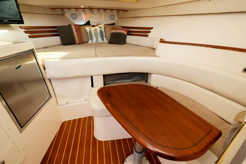 Slide: The Image of 2003 Grady-White Express 330 cabin interior with seating, kitchenette, and wood flooring. - 26