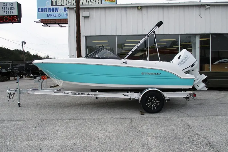 The Image of 2026 Stingray 172 DC boat on trailer, turquoise and white, parked outside dealership. - 1