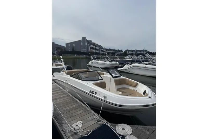 Slide: The Image of 2025 Bayliner VR6 Bowrider OB docked at marina, showcasing sleek design and spacious seating. - 2