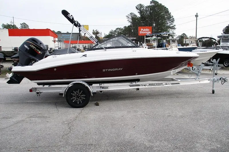 The Image of 2026 Stingray 191 DC boat on trailer, parked outdoors near storage facility. - 1