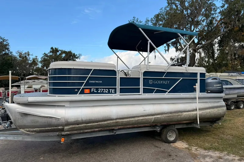 The Image of 2022 Sweetwater 2086 CX pontoon boat on trailer, featuring blue and white design. - 1