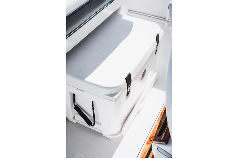 Slide: The Image of White cooler on 2026 Edgewater 262CC boat deck, secured with black straps. - 15