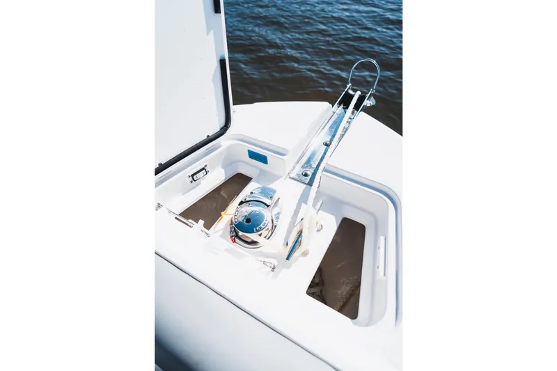 Slide: The Image of 2026 Edgewater 262CC boat anchor compartment with winch, open hatch, and water background. - 17