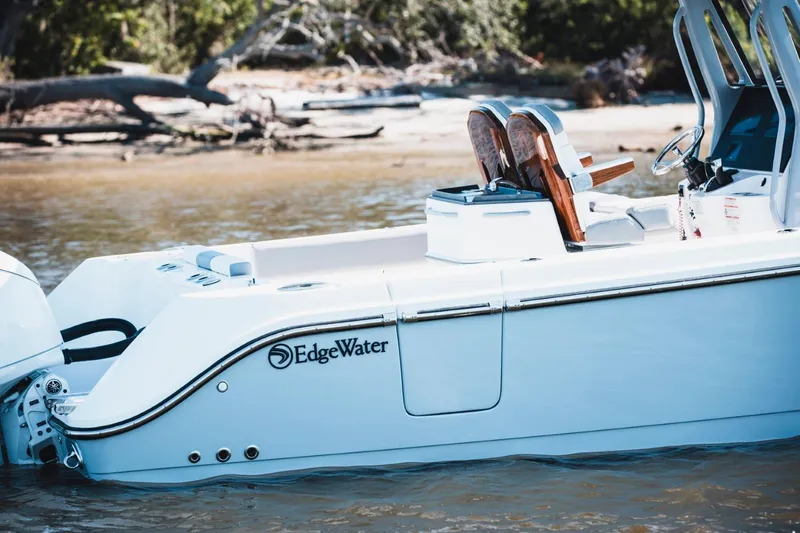 Slide: The Image of 2026 Edgewater 262CC boat on water near a sandy shore. - 2