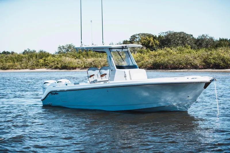 Slide: The Image of 2026 Edgewater 262CC boat on calm water near lush shoreline. - 3